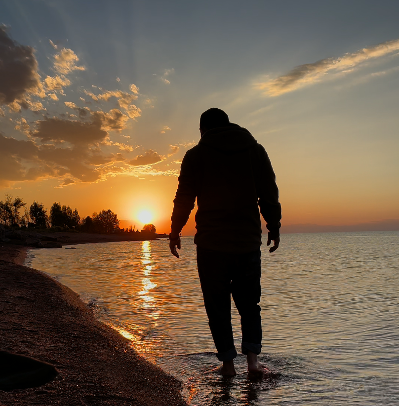 Traveler walking by a Kyrgyzstan lake at sunset